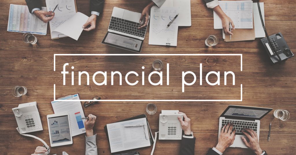 Financial Plan Written on A Table With Business People, Laptops, and Notebooks | Building A Financial Plan For The Future | Numerico