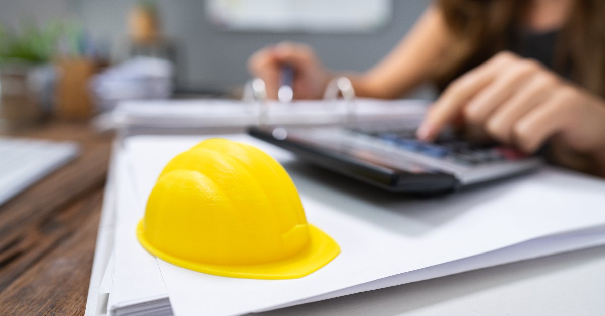 Michigan Construction Accounting Firm | Yellow Hard Hat On An Accountant's Desk With A 3 Rind Binder and Calculator | Numerico | Livonia, MI